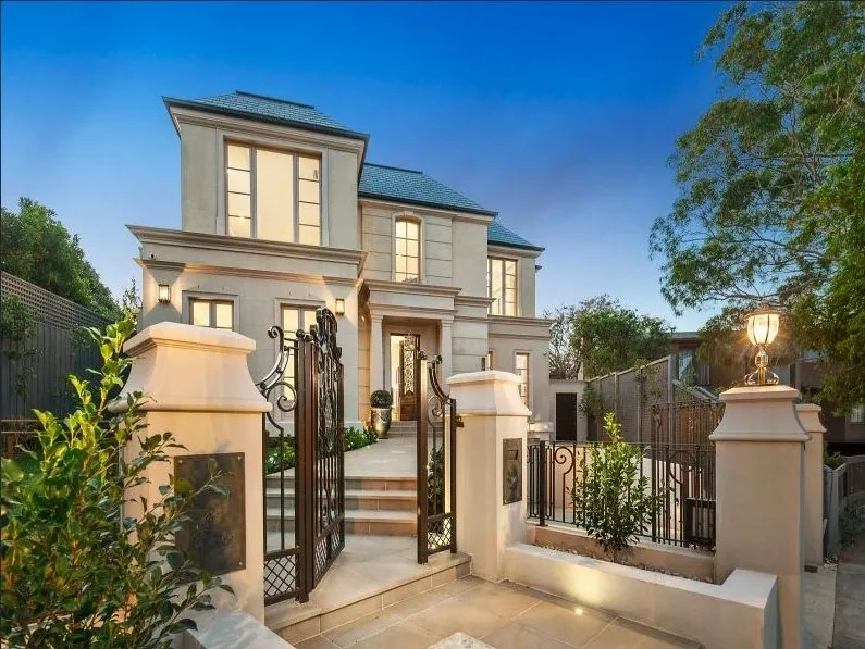 Angled front façade of the completed Kew residence with wrought-iron entrance gates